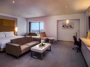 a hotel room with a bed and a couch at Grand Mercure Jakarta Harmoni in Jakarta