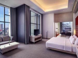 a bedroom with a bed and a tv and windows at Grand Mercure Jakarta Harmoni in Jakarta +75 photos