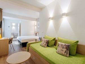 a hotel room with a bed and a green couch at Aparthotel Adagio Access Bruxelles Europe Aparthotel in Brussels +35 photos