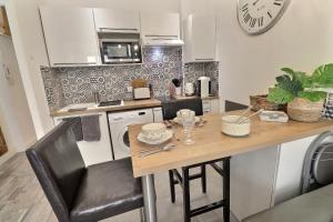 Una cocina con una mesa y un reloj en la pared. en Studio 4 personnes Hyper centre, en Cannes