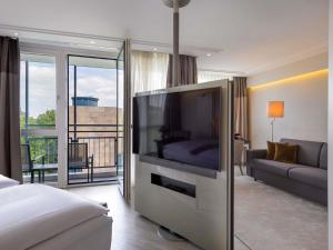 a living room with a large television in a hotel room at Pullman Munich in Munich