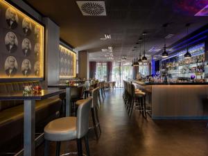 a restaurant with a bar with chairs and tables at Pullman Munich in Munich
