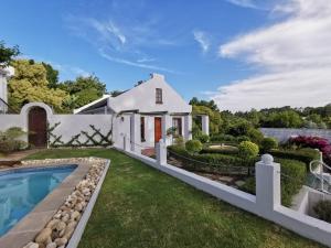 a white house with a swimming pool and a yard at Somerset Grace Cottage in Somerset West