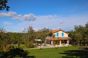 a white house with blue windows on a green yard at Villa Krug with 3 br and a pool immersed in nature near Buje in Kremenje
