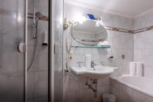 Un baño con lavabo y ducha con espejo. en Alpengasthof Pichler, en Sankt Veit in Defereggen 50 fotos más