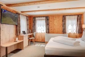 Un dormitorio con una cama y un escritorio con una computadora. en Alpengasthof Pichler, en Sankt Veit in Defereggen