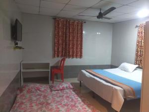 a bedroom with a bed and a table and a chair at Sai Samata Lodging Boarding in Junnar