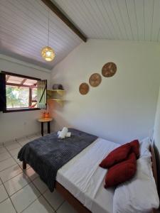 a bedroom with a bed with red pillows on it at Pousada Aconchego do Rosa - Centrinho do Rosa in Praia do Rosa