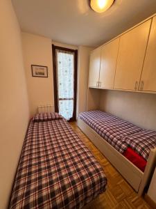a bedroom with two beds and a plaid blanket at Appartamento Bluebell in Santa Maria Maggiore