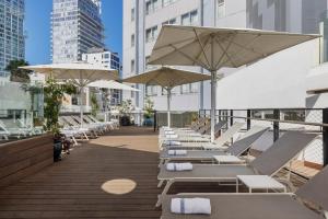 a row of lounge chairs and umbrellas on a deck at Metropolitan Hotel in Tel Aviv
