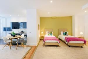 a bedroom with two beds and a table and a kitchen at Martinhal Lisbon Chiado in Lisbon