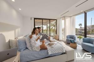 Ein Mann und eine Frau sitzen auf einem Sofa im Wohnzimmer. in der Unterkunft Carlotta- New Construction Luxury Waterfront Villa in Fort Lauderdale