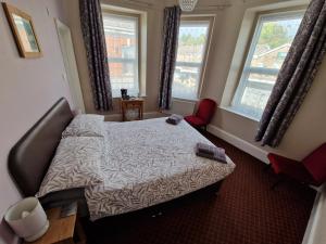 a bedroom with a bed and two windows at The Swan Hotel in Lydney