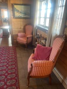 a living room with two chairs and a rug at Charming Timber Lodge For Gathering And Celebrations in Beitostøl