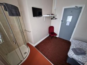 a small bathroom with a shower and a red chair at The Swan Hotel in Lydney