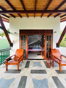 two wooden chairs sitting on a porch with a patio at Shells Villa Hikkaduwa in Hikkaduwa +28 photos