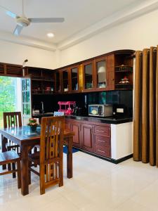 a kitchen with wooden cabinets and a table and chairs at Shells Villa Hikkaduwa in Hikkaduwa