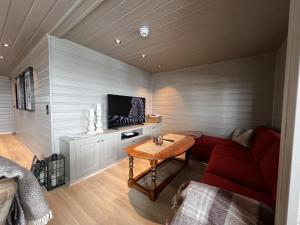 Una sala de estar con un sofá rojo y una mesa. en Large Balcony With Panoramic Mountain Views, en Beitostølen