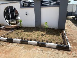 un cortile con due piante di fronte a un edificio di Amdeal Apartment a Kaduna