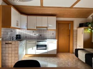 a kitchen with white cabinets and a stove at Bergmanns Ferienapartment in Debant +26 photos