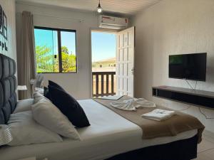 a bedroom with a large bed with a flat screen tv at Pousada Anjos - à 2 quadras do mar in Matinhos
