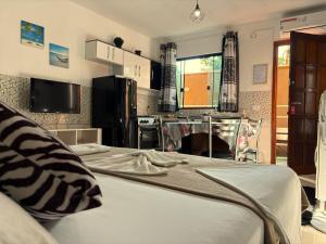 a bedroom with a large bed and a kitchen at Pousada Anjos - à 2 quadras do mar in Matinhos