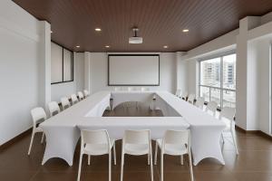 a conference room with a large white table and chairs at Hotel CGH Travel INN Airport in Bogotá