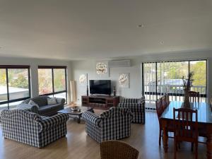 un salon avec des canapés, une table et une télévision dans l'établissement The Hobson Dual Living, close to surf beach and pet friendly, à Inverloch