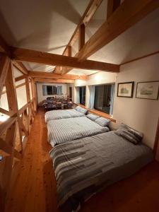 高森町にある閼宗屋 Asoyaのベッド4台、木製の梁があるウッドフロアの客室です。