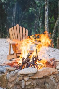 a fire pit with a wooden chair and a chair at Luxury Cabin at 1,600m altitude in São Bento do Sapucaí
