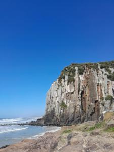 a large rocky cliff next to the ocean at Recanto praiano in Torres