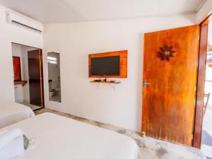 a bedroom with a door and a tv on the wall at Pousada do Enildo in São Miguel dos Milagres