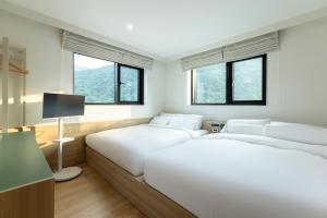two beds in a hotel room with windows at 호텔 리브몬트 단양 by 아늑 