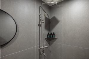 a shower with a glass door with bottles on a shelf at Hotel Rivmont Danyang by Anook in Danyang +113 photos