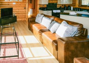 a living room with brown leather couches and a kitchen at Laxfield Lodges in Laxfield +3 photos