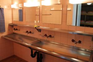 a bathroom with a stainless steel sink and mirrors at Pension St. Jakob in Engelberg +32 photos