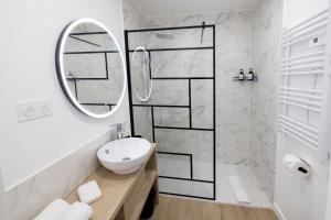 a white bathroom with a sink and a mirror at Le Vert Olivier- Studio tout confort in Montluçon