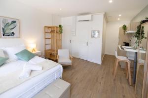 a bedroom with a white bed and a kitchen at Le Vert Olivier- Studio tout confort in Montluçon
