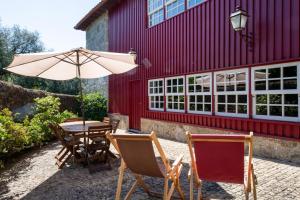 a table and chairs and an umbrella in front of a building at Recantos na Portela in Amares +22 photos