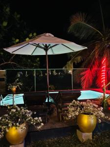 an umbrella sitting next to a bench and a pool at Shells Villa Hikkaduwa in Hikkaduwa