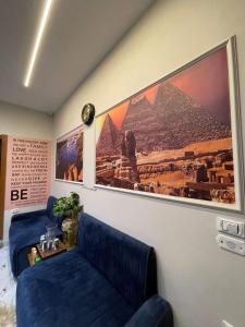 カイロにあるCairo Excellent Location hotelの青い椅子2脚とピラミッドの絵が飾られた部屋