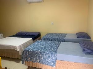 a room with three beds with blue and white sheets at Hotel Arara Azul in Pontes e Lacerda