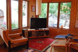 a living room with a flat screen tv and windows at A nice view, panorama over Lago Maggiore in Ronco sopra Ascona