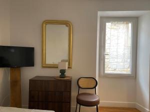 a bedroom with a mirror and a chair and a television at le cocon du beffroi centre ville in Millau