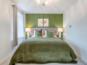 a bedroom with a large green bed with two lamps at Warrington House-Uk48465 in Thornton Dale