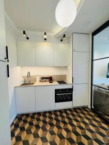 Una cocina con gabinetes blancos y piso a cuadros. en Amber Circle Apartment Palanga, en Palanga