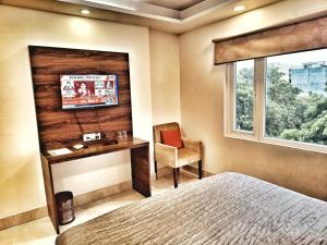 a bedroom with a bed and a desk and a television at Hotel Aerocity Purple Orchid in New Delhi