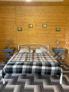 a bed in a wooden room with two tables at Панорама Шаян in Shaian