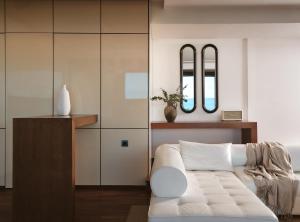 a living room with a white couch and two mirrors at Lesante Blu - The Leading Hotels of the World, Adults Only in Tragaki