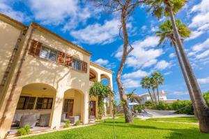 a house with palm trees in the yard at Casa Leo in Playa de Muro